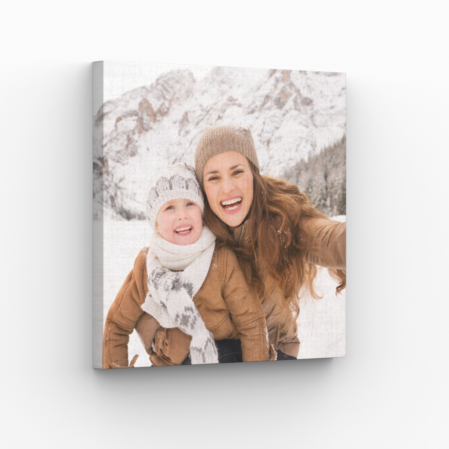 A wrapped canvas print of a mother and child enjoying the snow, hanging on a white wall.