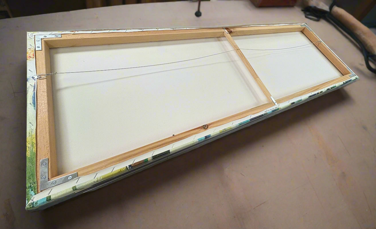 Back of panoramic canvas showing the wood bars and hanging wire on work table.