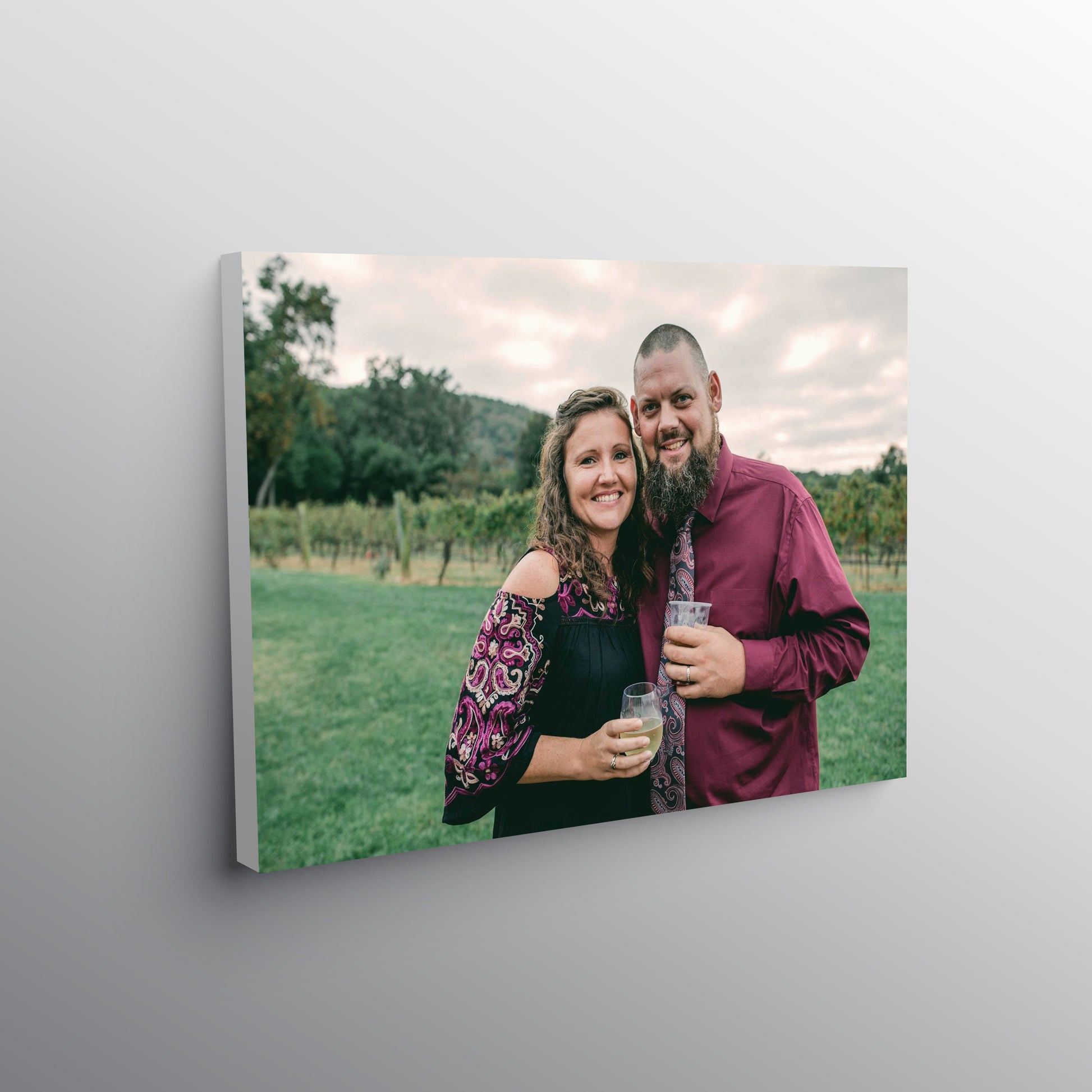 A stretched canvas print of a couple in a vineyard, hanging on a gray wall.